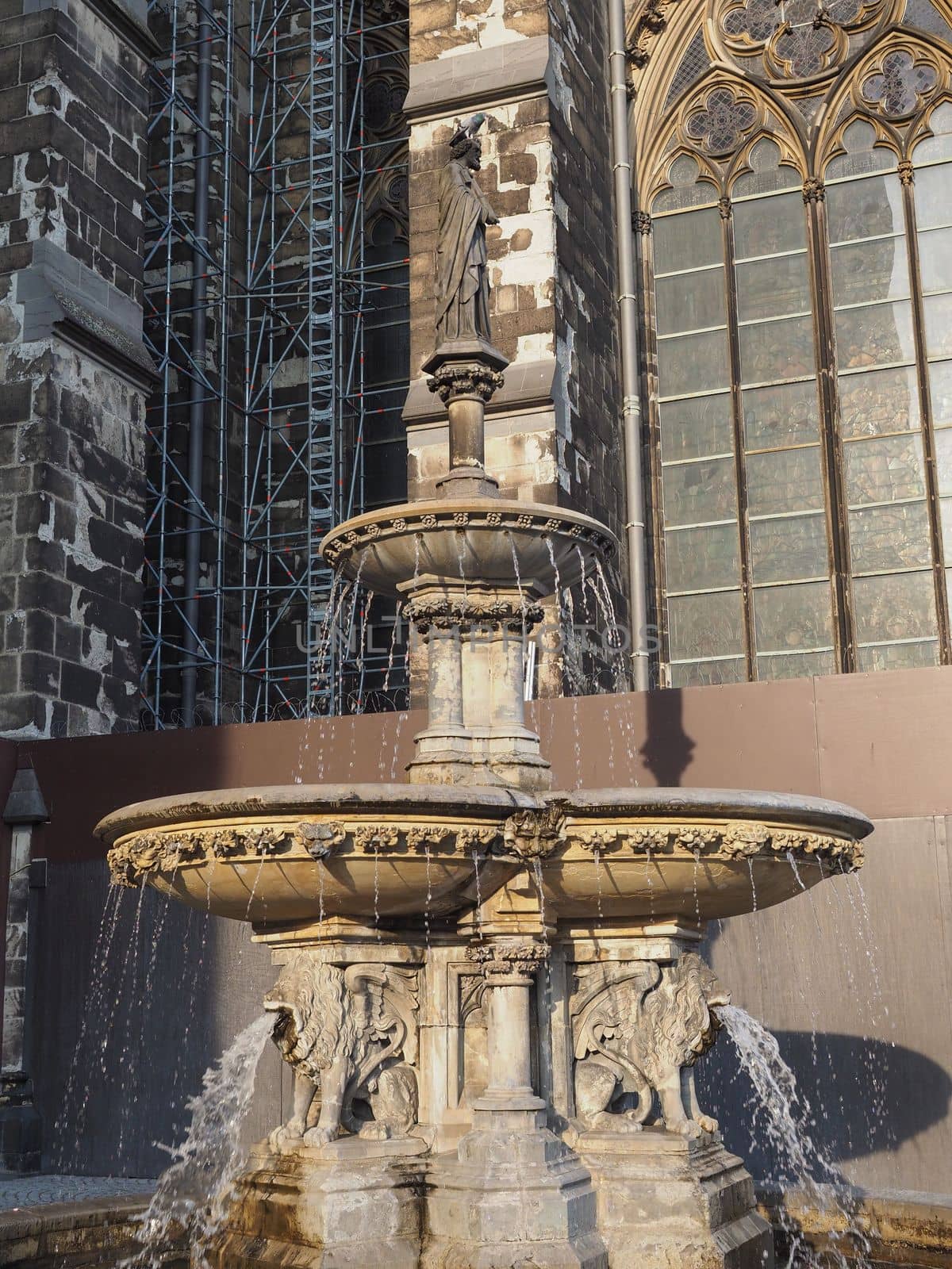 Petrusbrunnen (meaning St Peter fountain) by the Koelner Dom Hohe Domkirche Sankt Petrus (meaning St Peter Cathedral) gothic church in Koeln, Germany