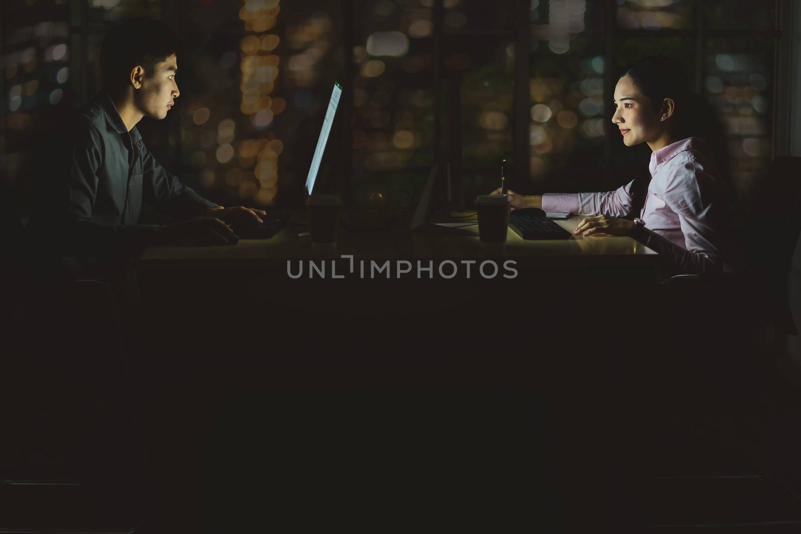 Asian business woman and business man working hard late together with technology computer in office, customer service and call center, team work with colleagues for success achievement project concept