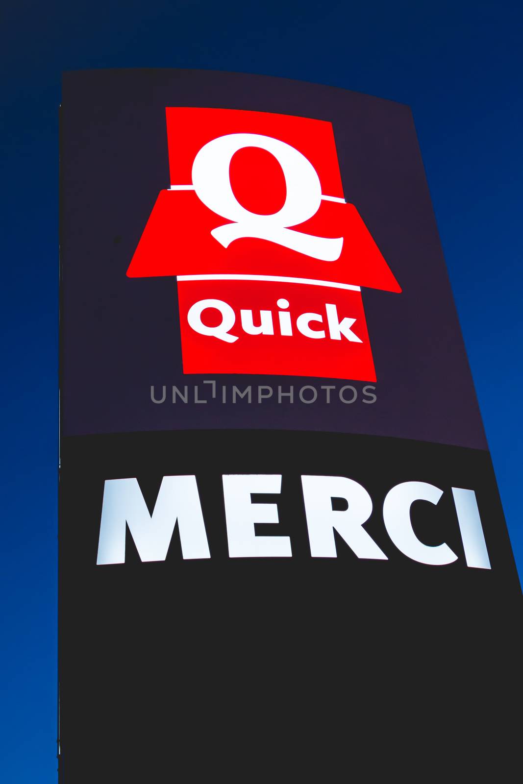 Olonne sur Mer, France - December 03, 2016 : Signs of the restaurant chain specialized in burgers "Quick" by night. The sign, located at the exit of the parking lot, bears the mention Thank you "Merci" in french