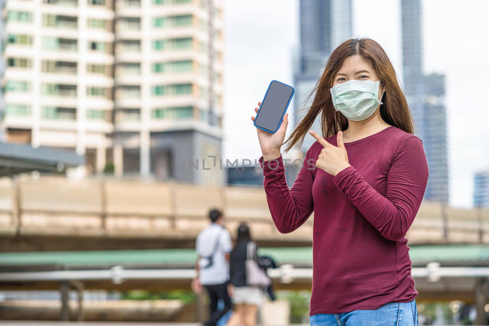 Asian woman hand showing smart mobile phone with safety medical face mask for prevent Coronavirus or Covid19 Outbreak when travel to work in business downtown, Health care and infection concept