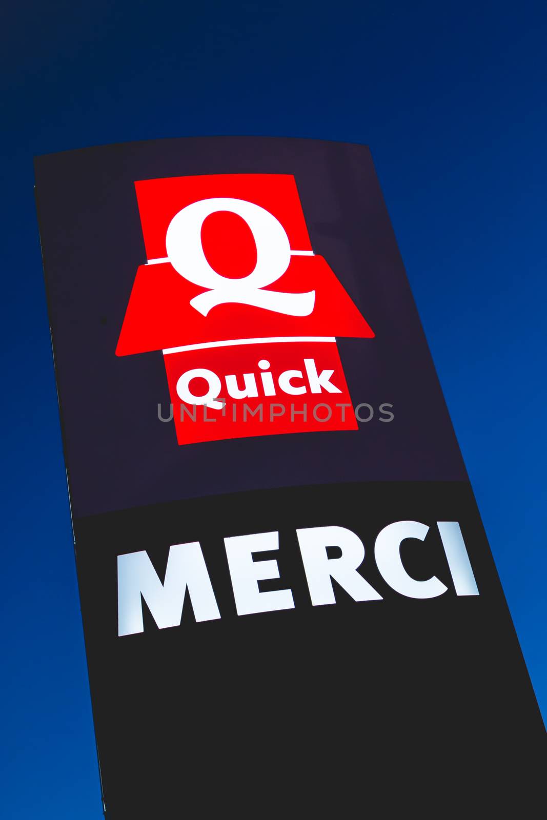 Olonne sur Mer, France - December 03, 2016 : Signs of the restaurant chain specialized in burgers "Quick" by night. The sign, located at the exit of the parking lot, bears the mention Thank you "Merci" in french
