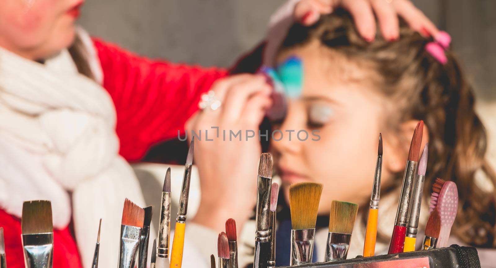 Bretignolles sur Mer, France - December 18, 2016 : During the Christmas period, a little girl is applying makeup in a stand on a Christmas market