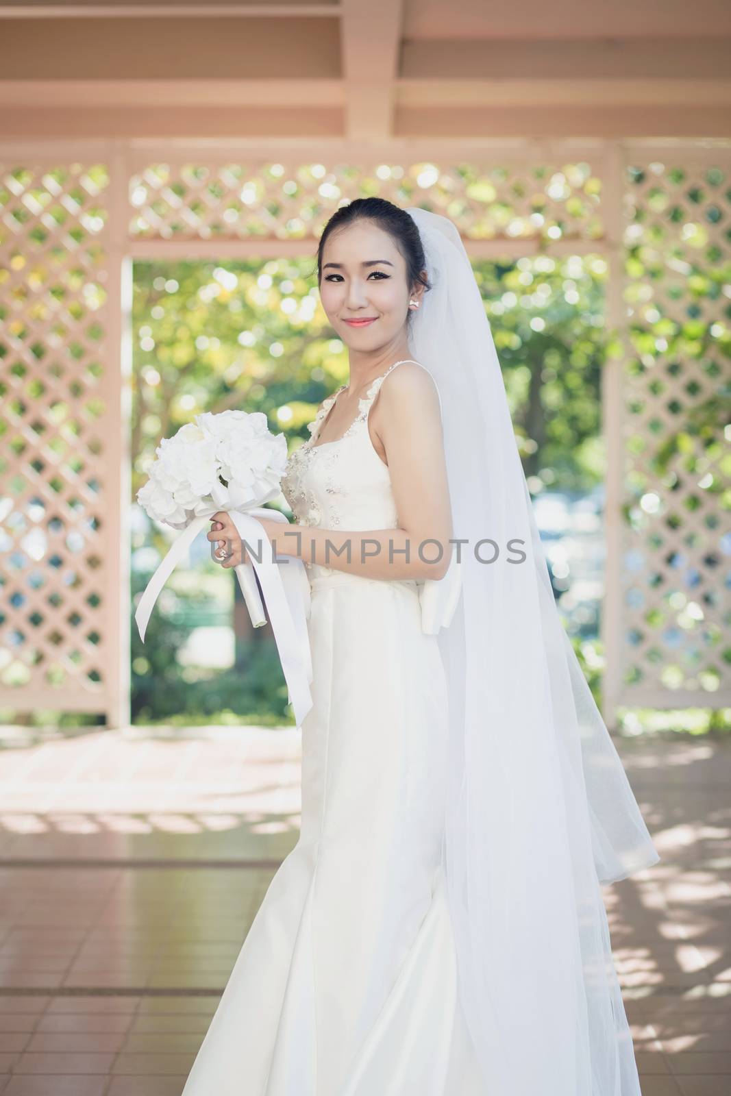 beautiful young woman on wedding day in white dress in the garden. Female portrait in the park.