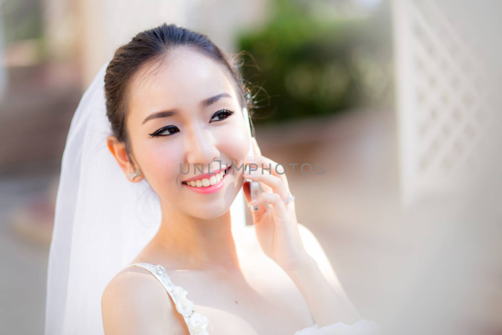 Happy bride talking on cell phone in wedding dress