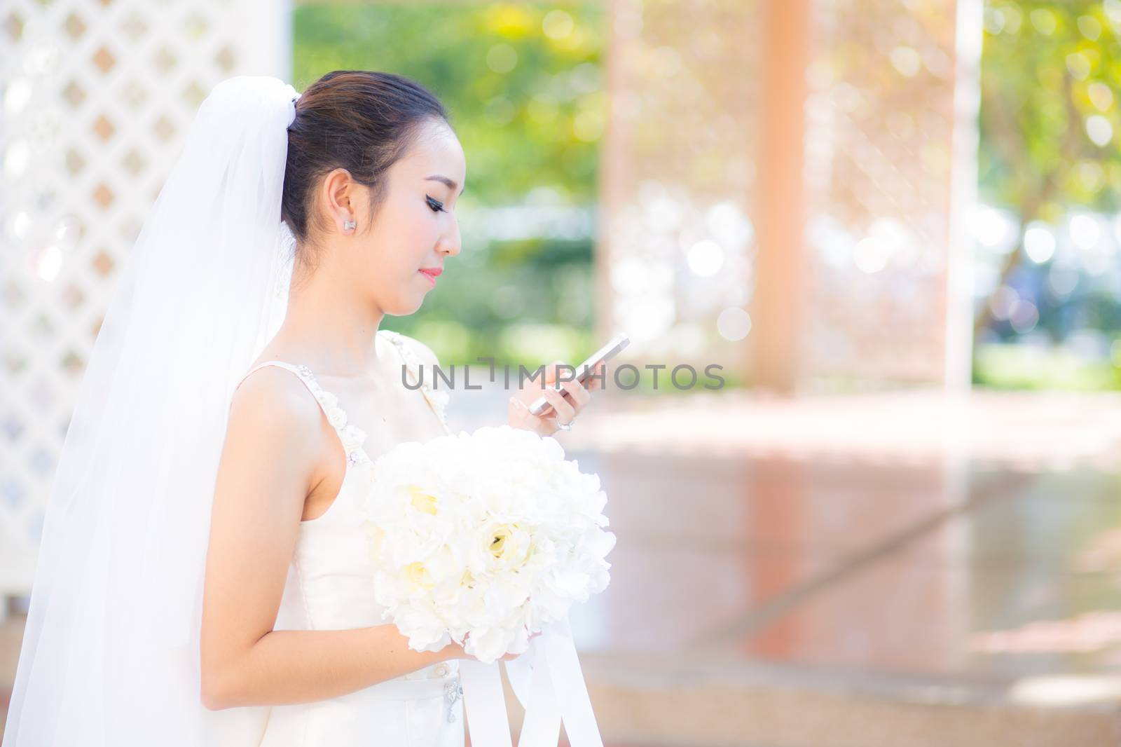 Happy bride talking on cell phone in wedding dress