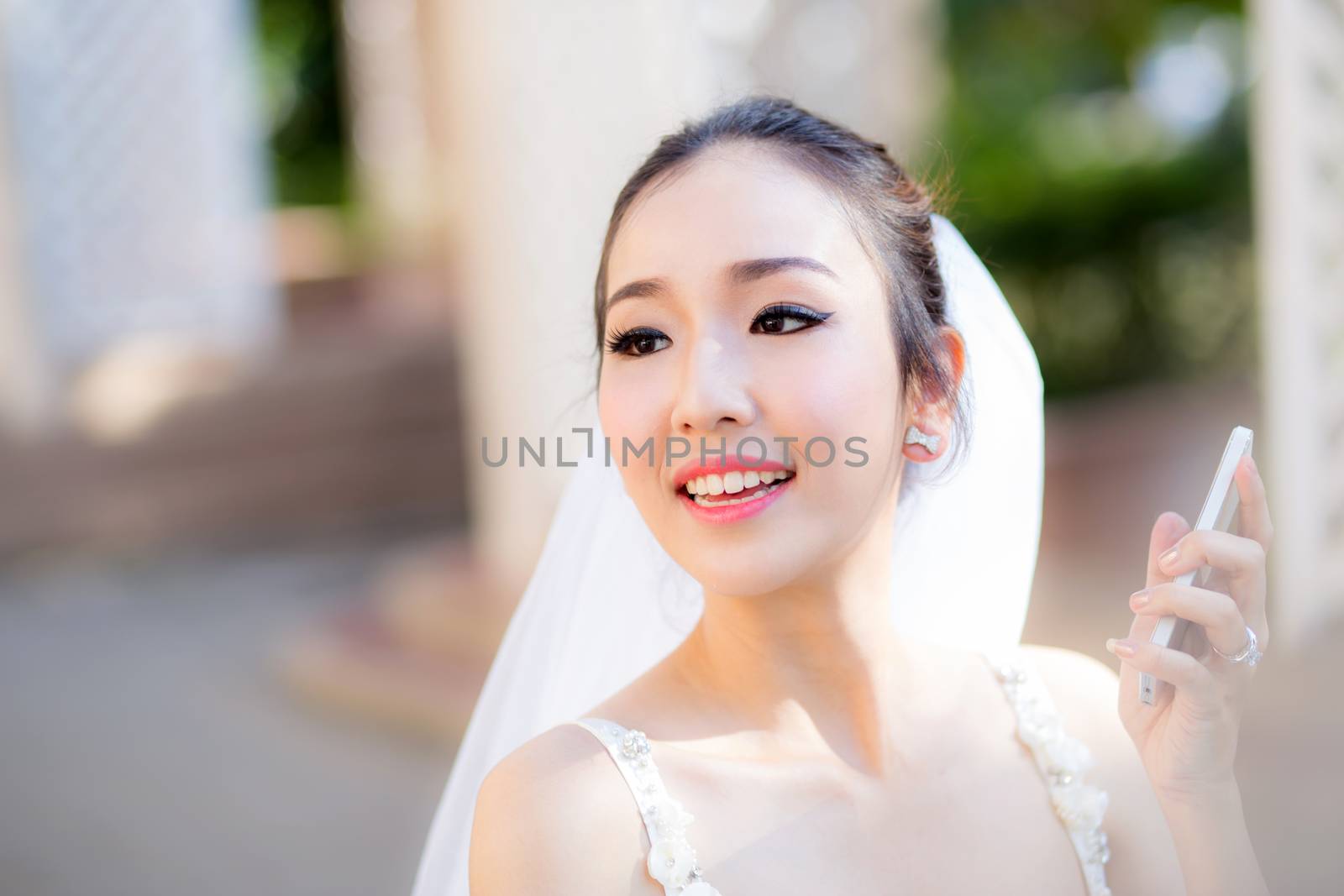 Happy bride talking on cell phone in wedding dress by nnudoo
