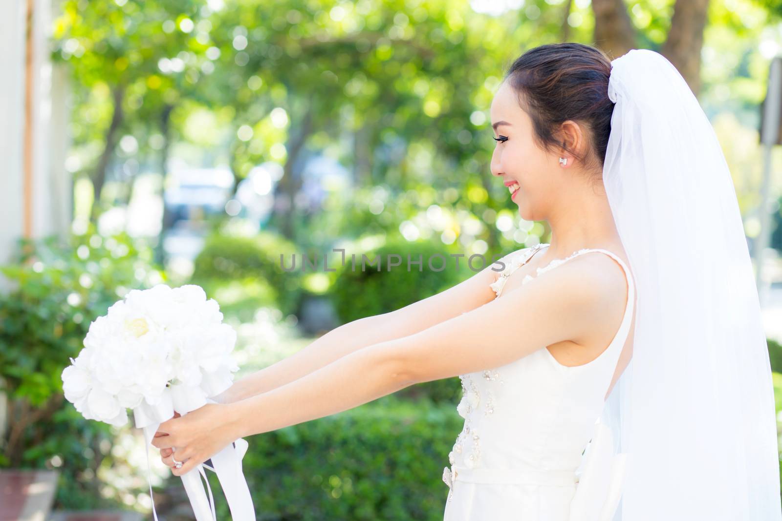 beautiful young woman on wedding day in white dress in the garden. Female portrait in the park.