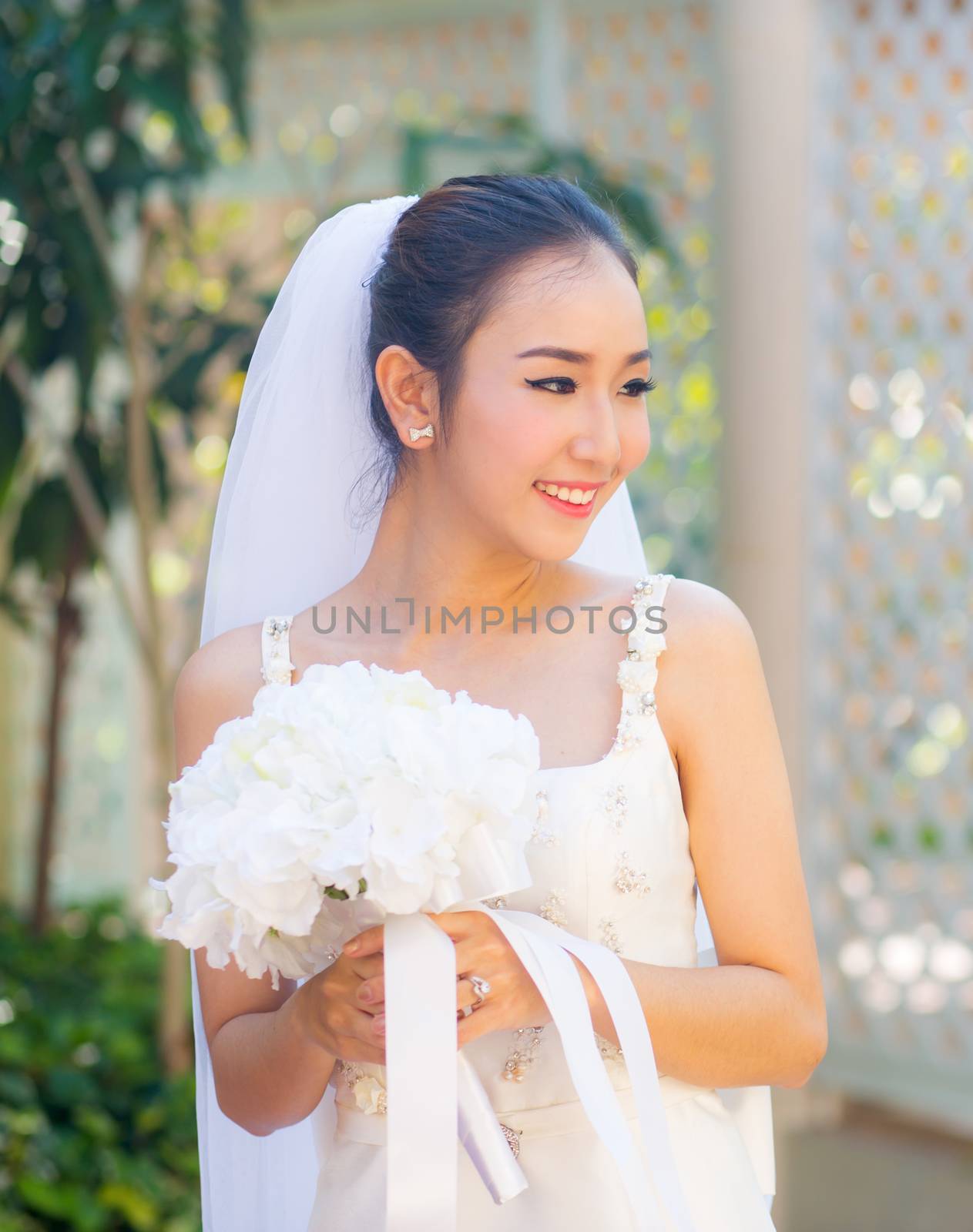 beautiful young woman on wedding day in white dress in the garden. Female portrait in the park.