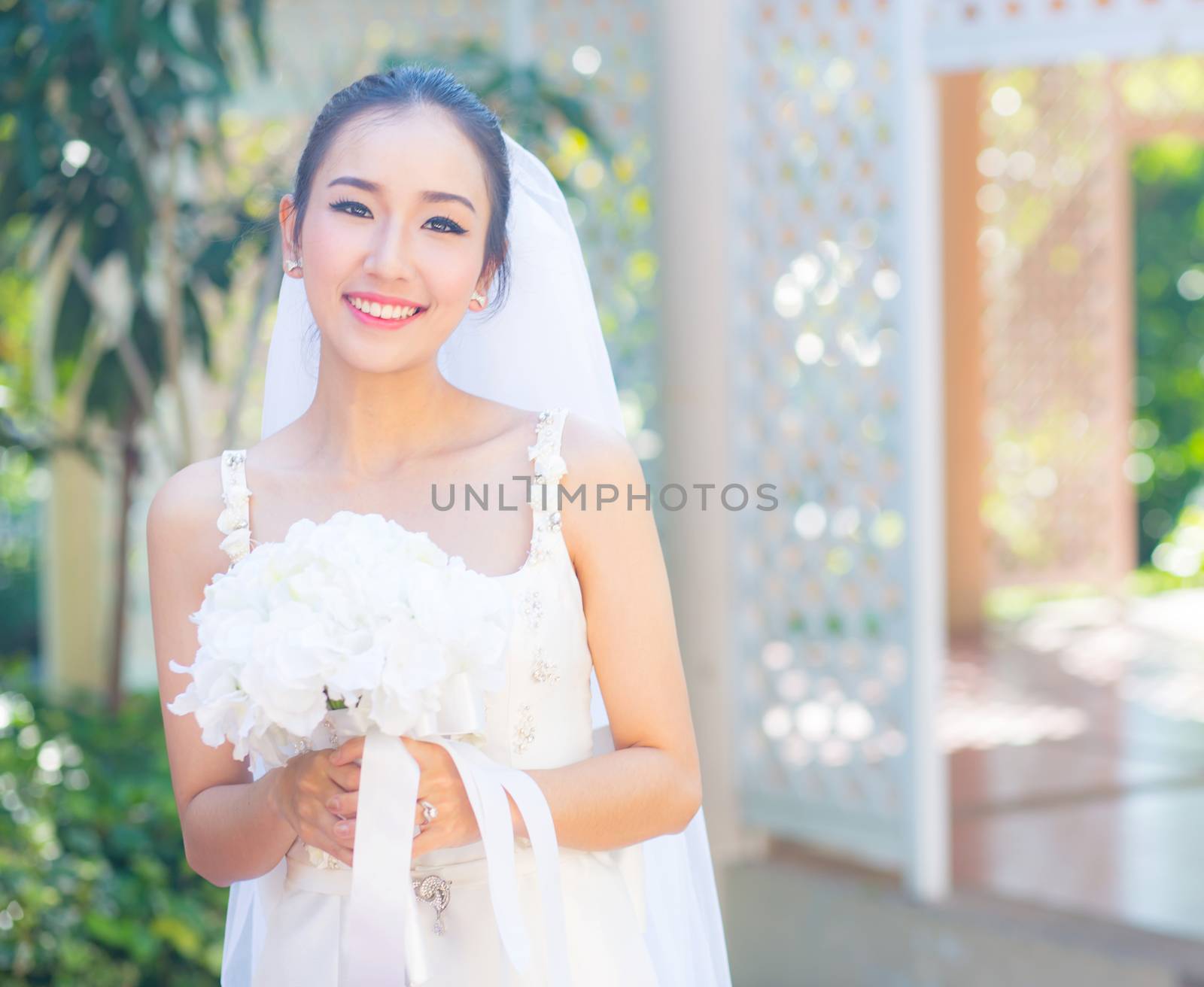 beautiful young woman on wedding day in white dress in the garden. Female portrait in the park.