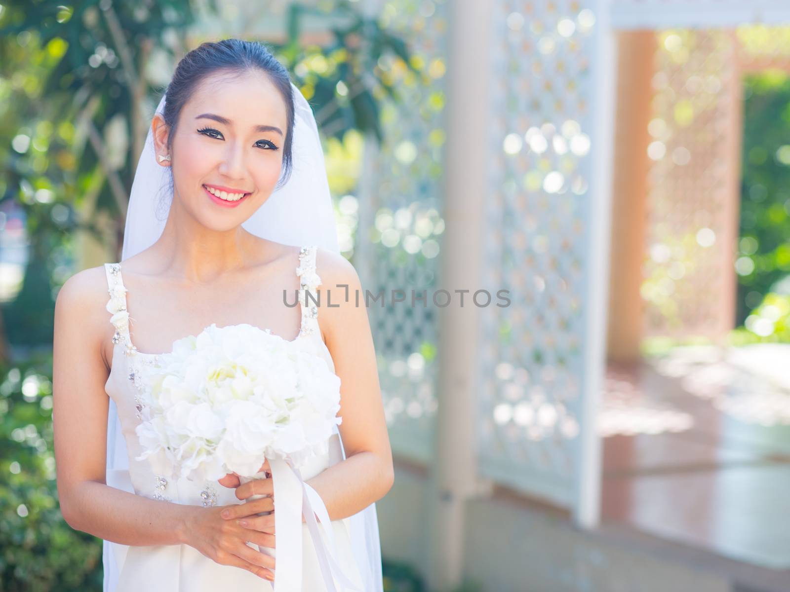 beautiful young woman on wedding day in white dress in the garden. Female portrait in the park.