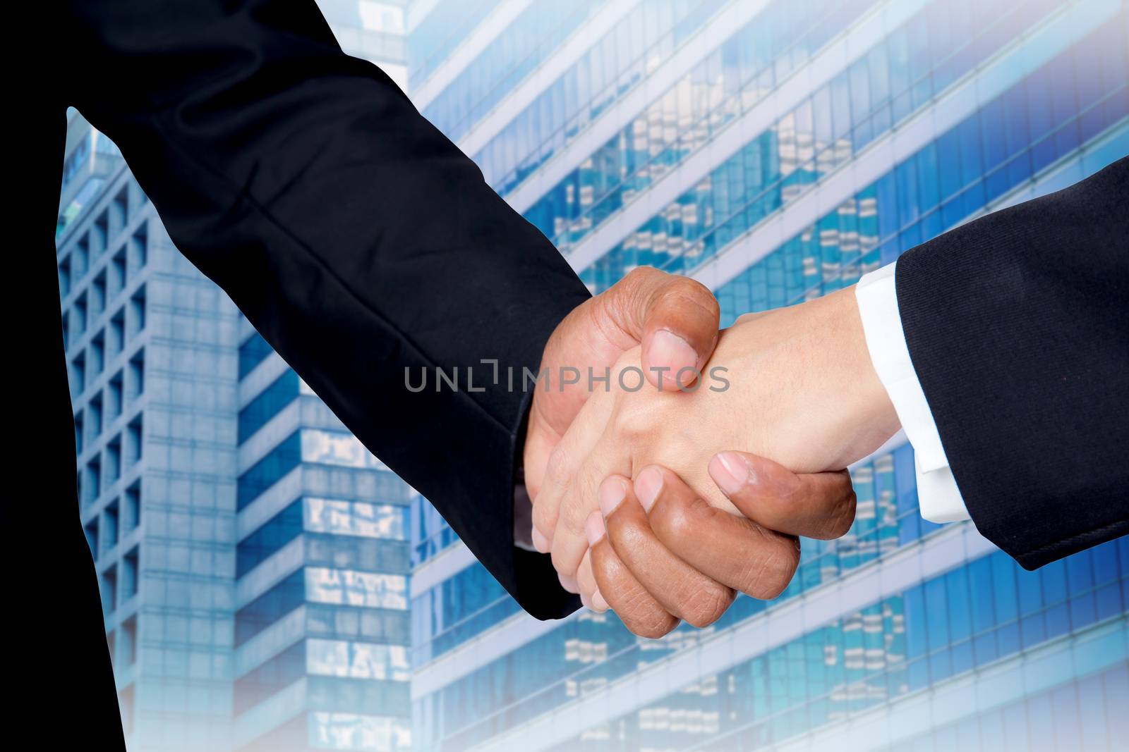 Hand shake between a businessman and a businesswoman with buildi by nnudoo