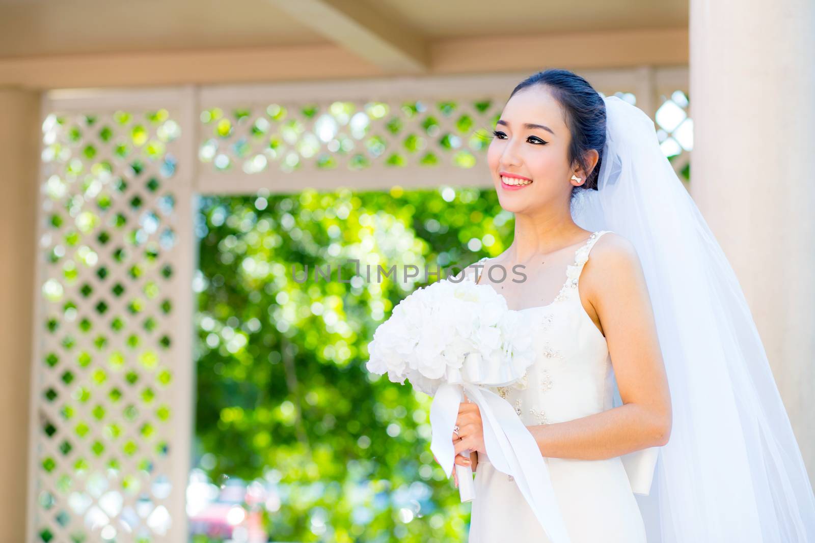 beautiful young woman on wedding day in white dress in the garden. Female portrait in the park.