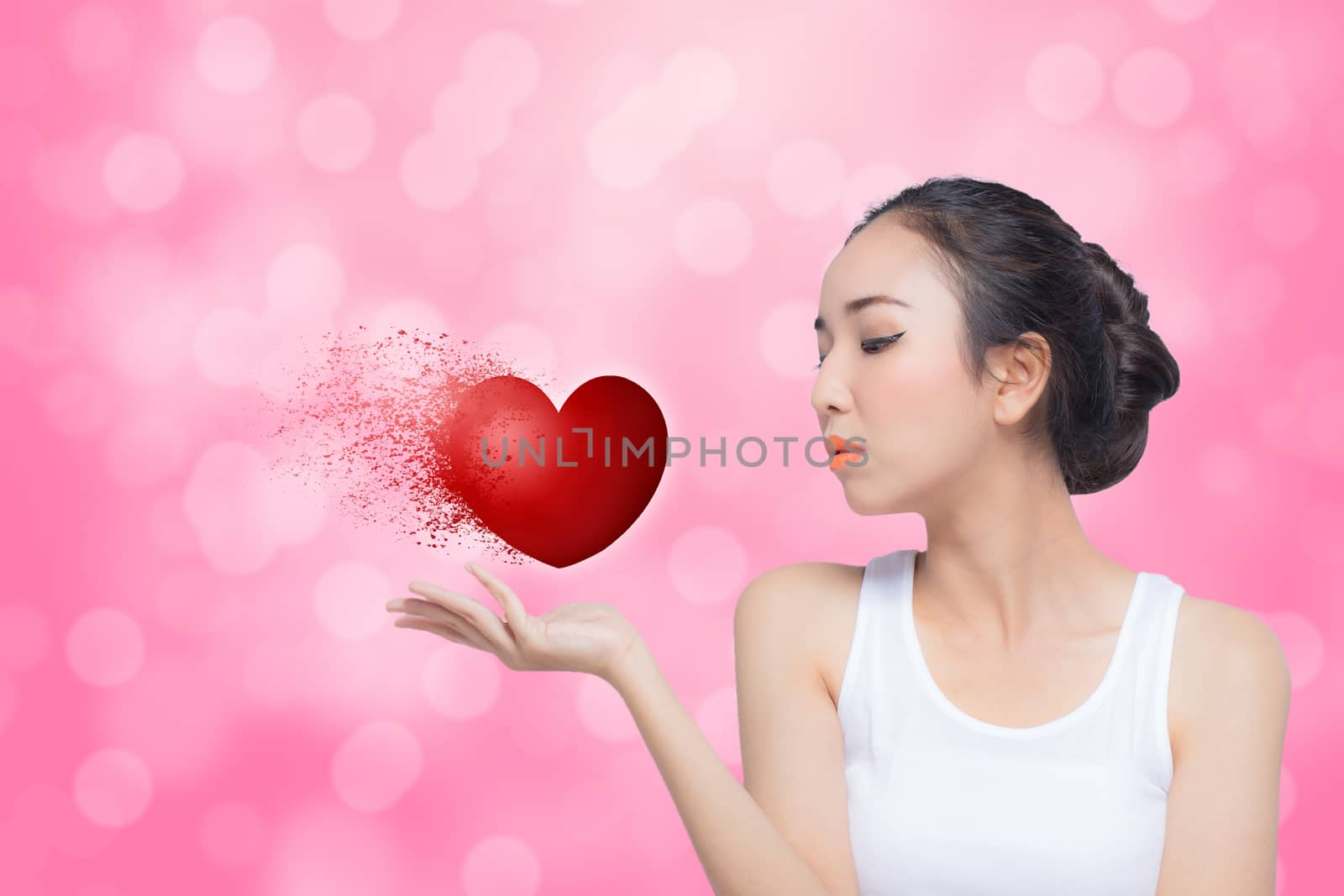 Woman celebrating Valentines day blowing red heart with bokeh pi by nnudoo