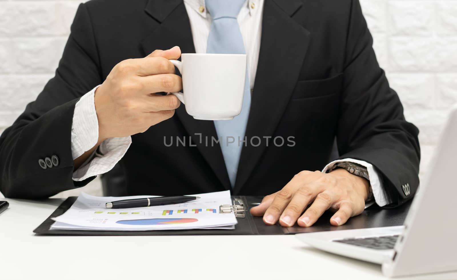 Businessman executive working on laptop at his desk and drinking coffee.