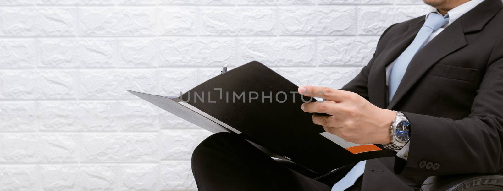 business man working on documents looking on a chair by sompongtom