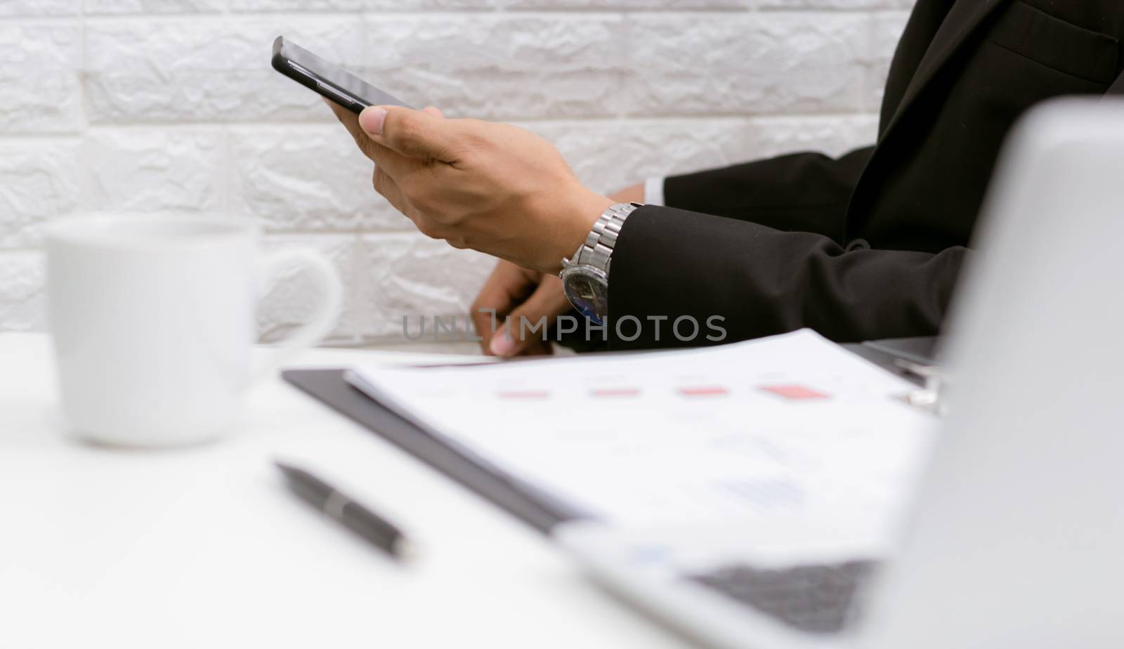 Business men hold smartphones to check information at the office by sompongtom