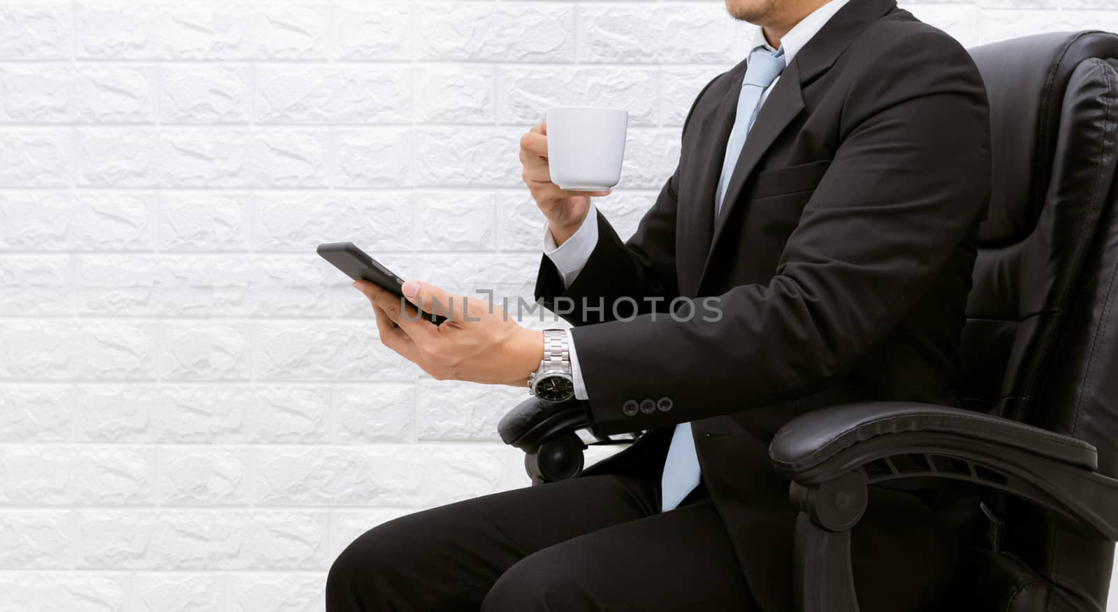 Coffee break businessman Hold a smartphone executive working relax on laptop at his desk.