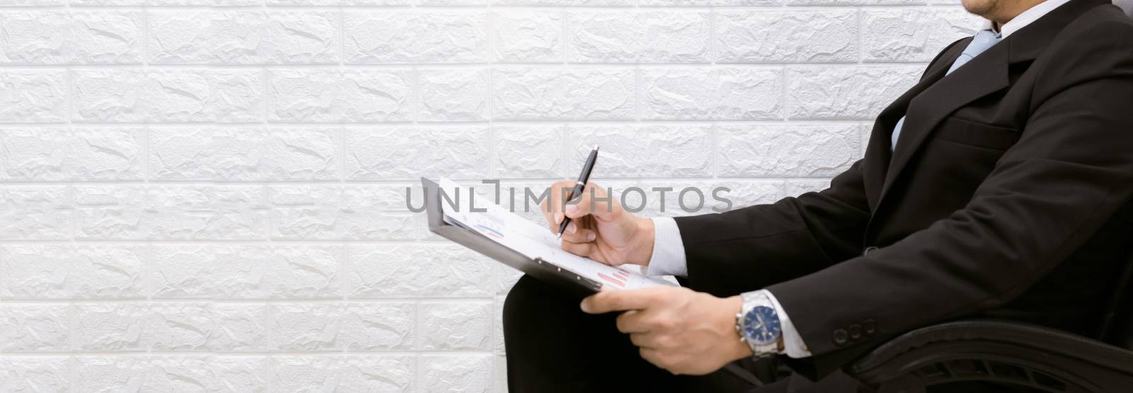 business man working on documents looking on a chair by sompongtom