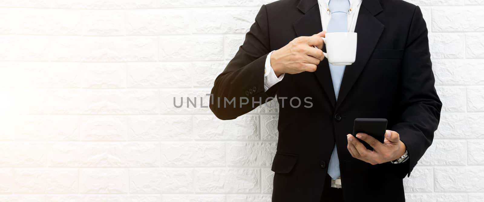 Coffee break businessman Hold a smartphone executive working relax on laptop at his desk.