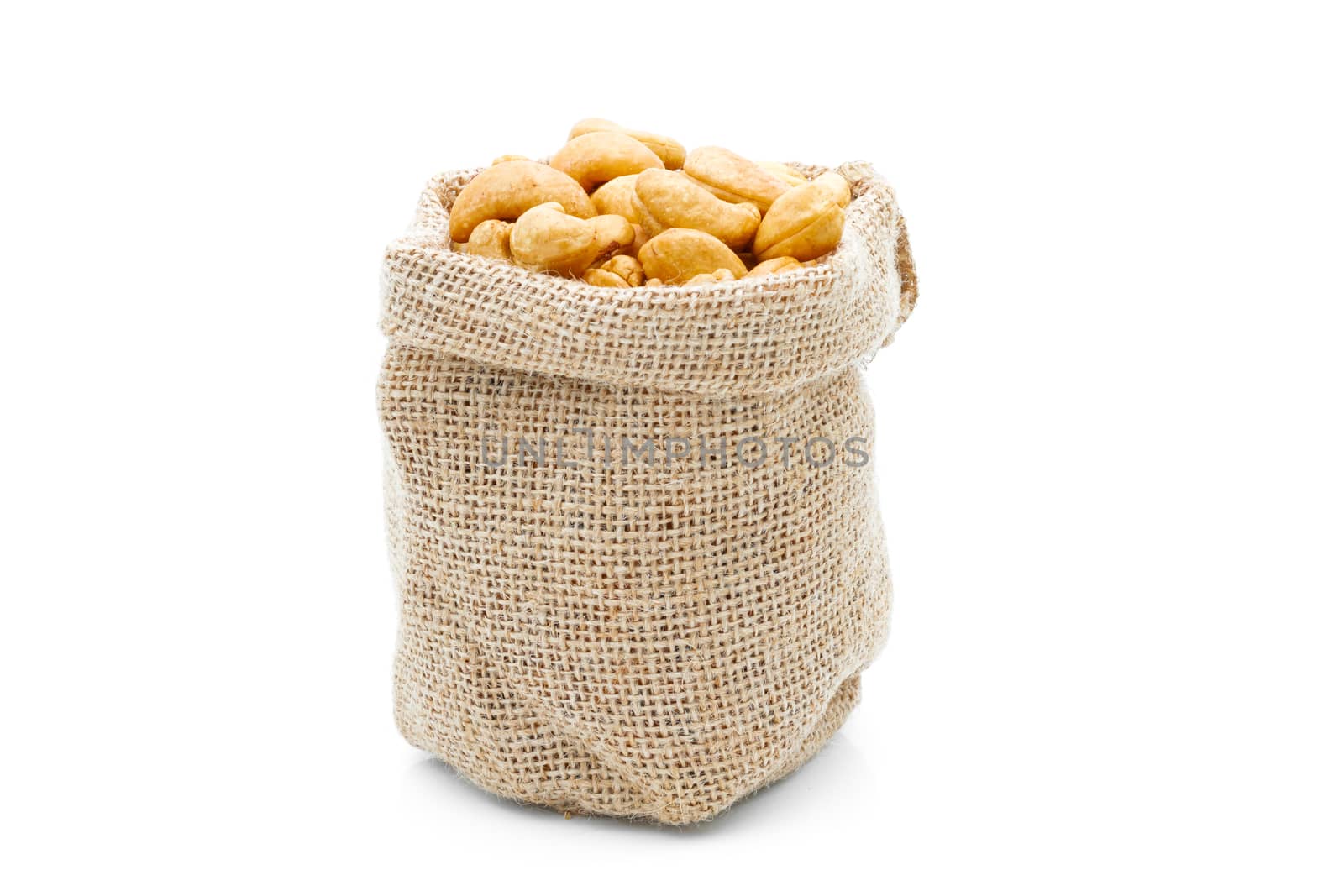 Cashews in a sack on a white background by sompongtom