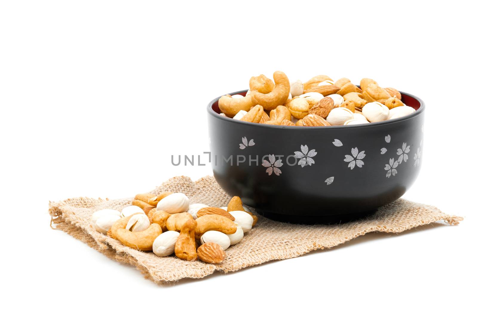 Almonds Pistachio and Cashews on a sack of cloth a white background by sompongtom