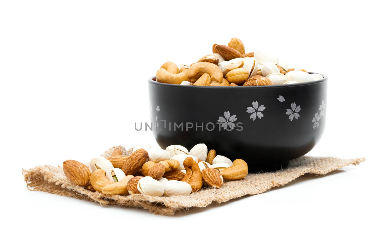 Almonds Pistachio and Cashews on a sack of cloth a white background by sompongtom