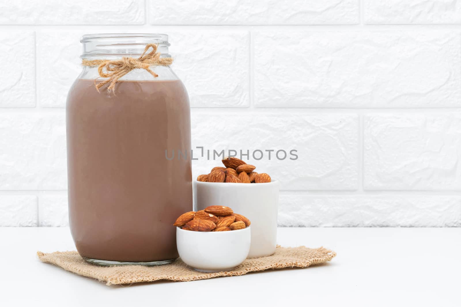 Milk Chocolate and Almonds in a glass on a white background by sompongtom