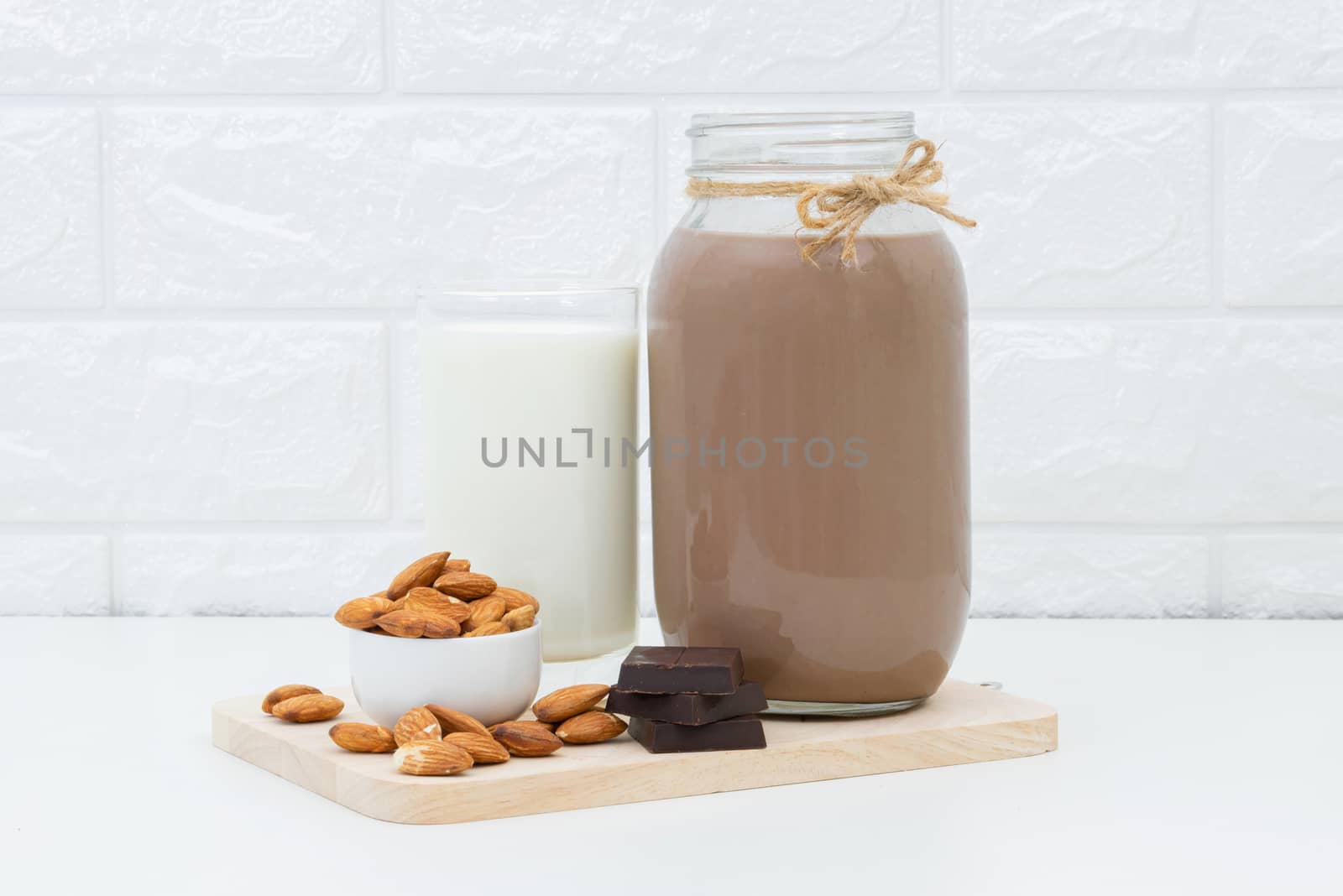 Milk Chocolate and Almonds in a glass on a white background by sompongtom