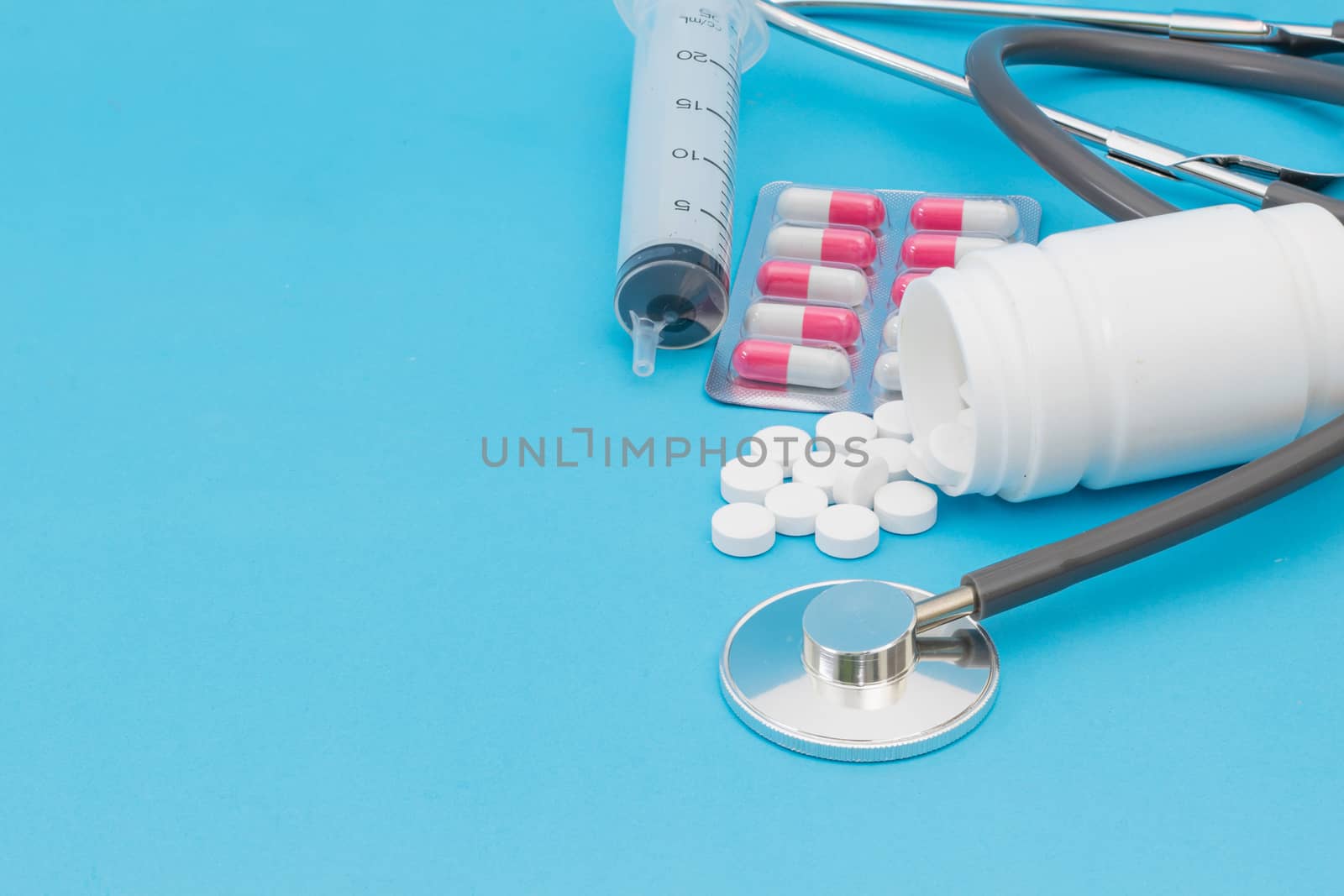 Tablet medical stethoscope and injection on a blue background