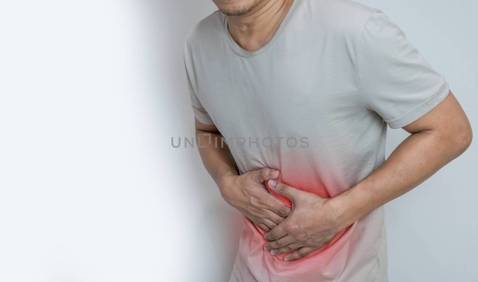 Man suffering from stomach ache with both palm around waistline to show pain and injury on belly area by sompongtom