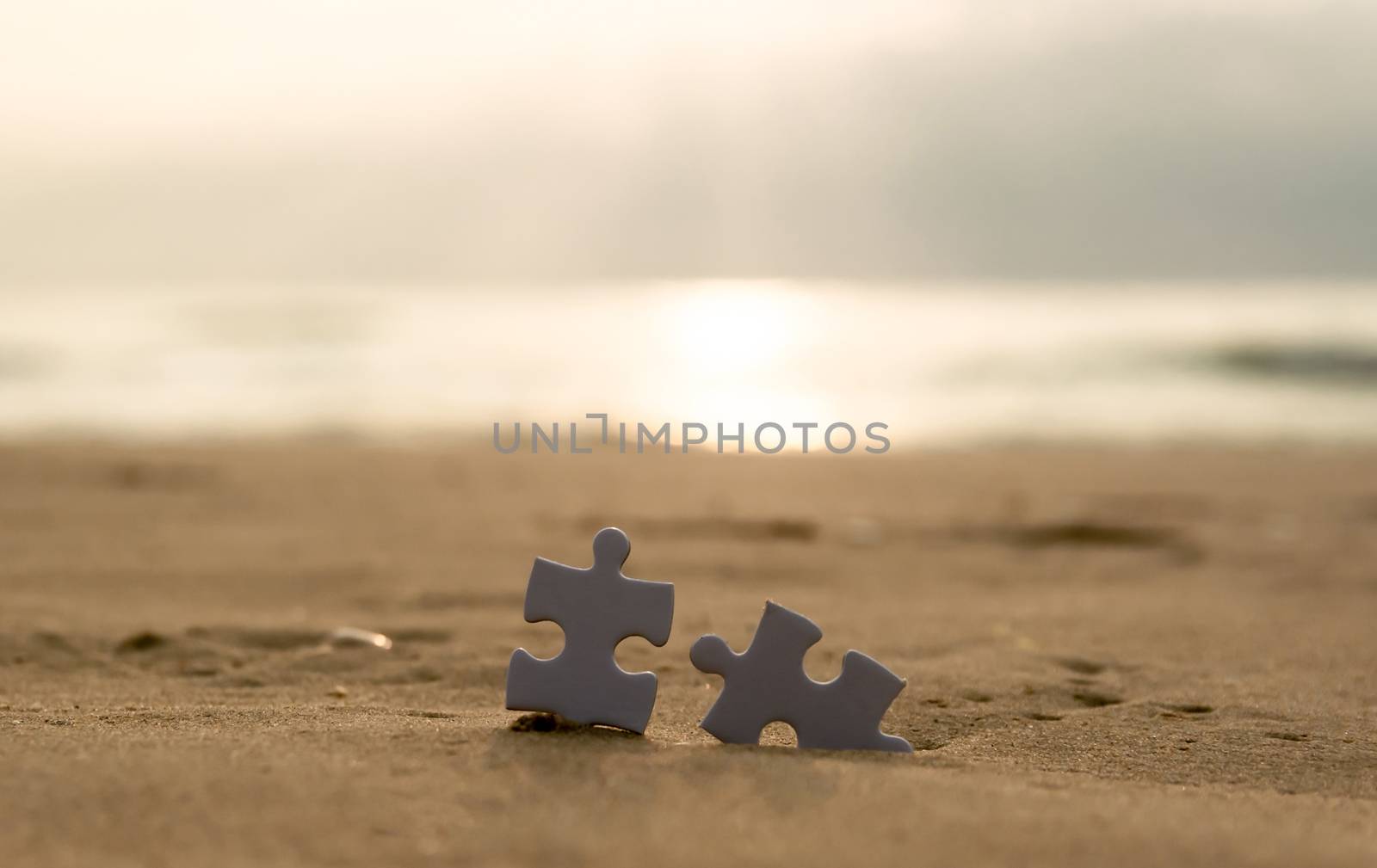 Jigsaw on the beach sand matching puzzle pieces together by sompongtom