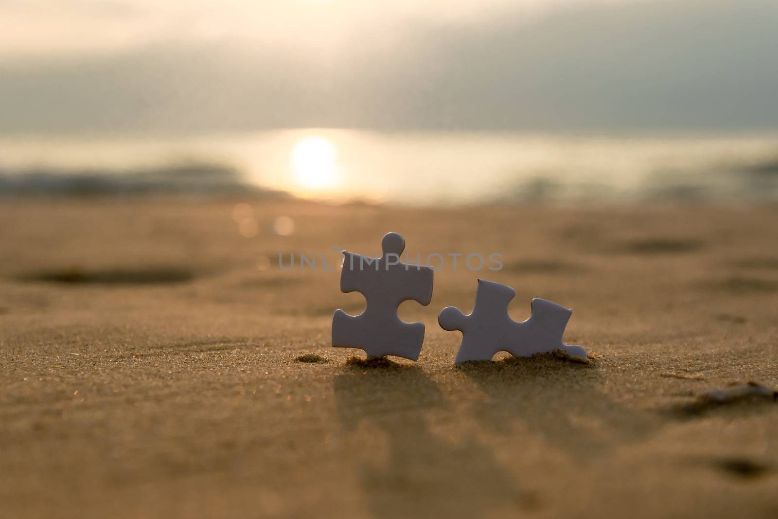 Jigsaw on the beach sand matching puzzle pieces together by sompongtom