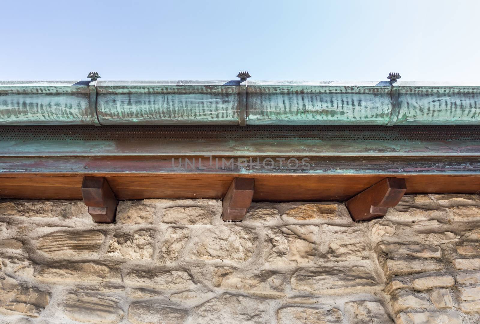 Vintage house with copper gutter, wooden beams and stone wall.