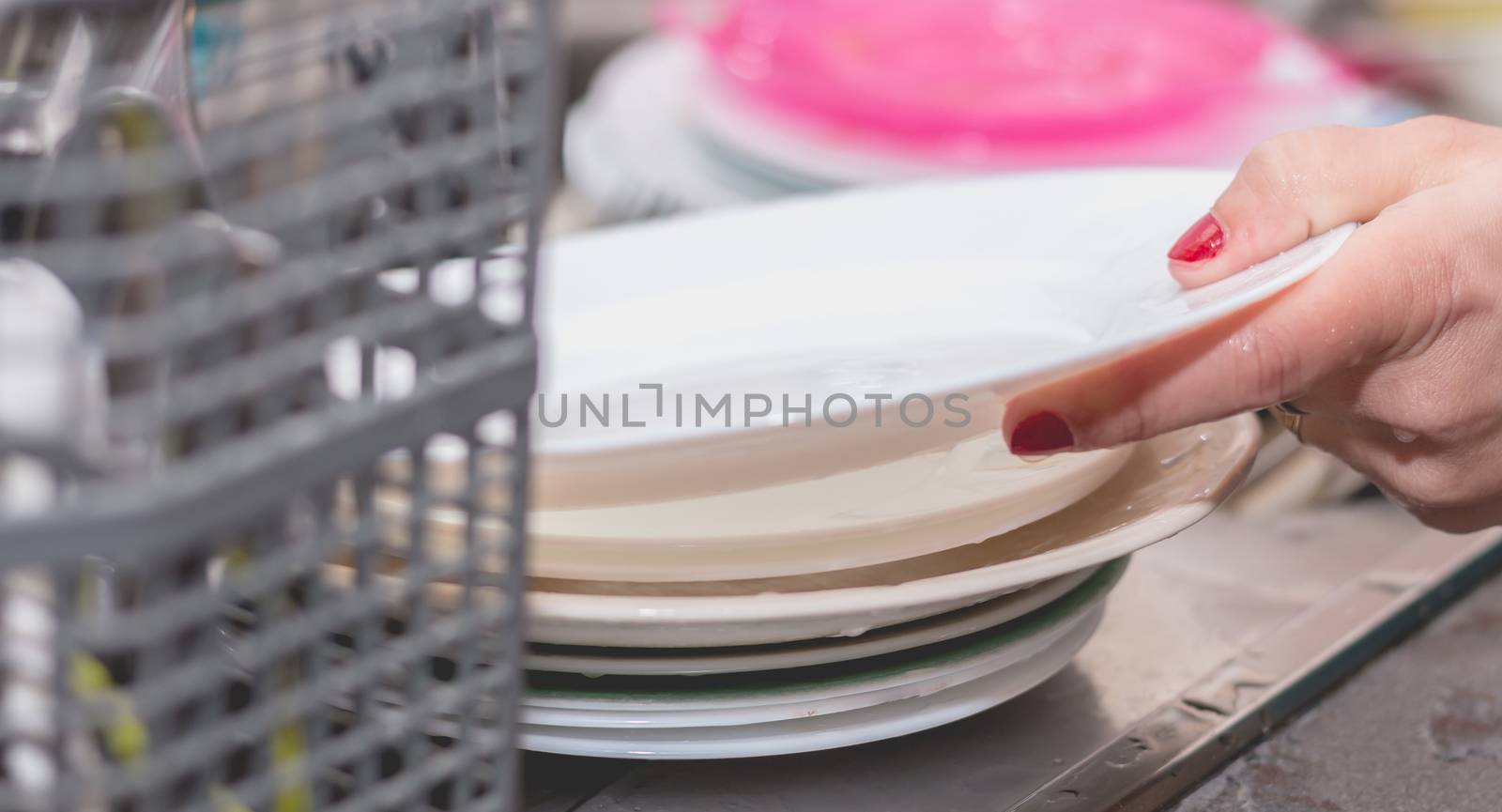 Close-up of a woman's hand filling a dishwasher machine