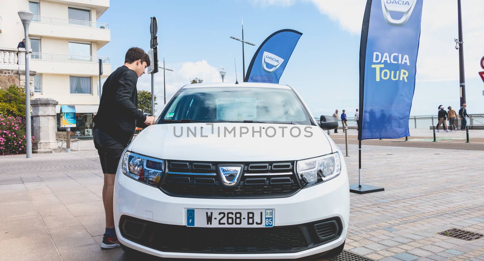 Sables d Olonnes, France - May 07, 2017 : Dacia Tour 2017 is a commercial operation organized by the car builder in order to present its cars throughout France - A young man watching a car