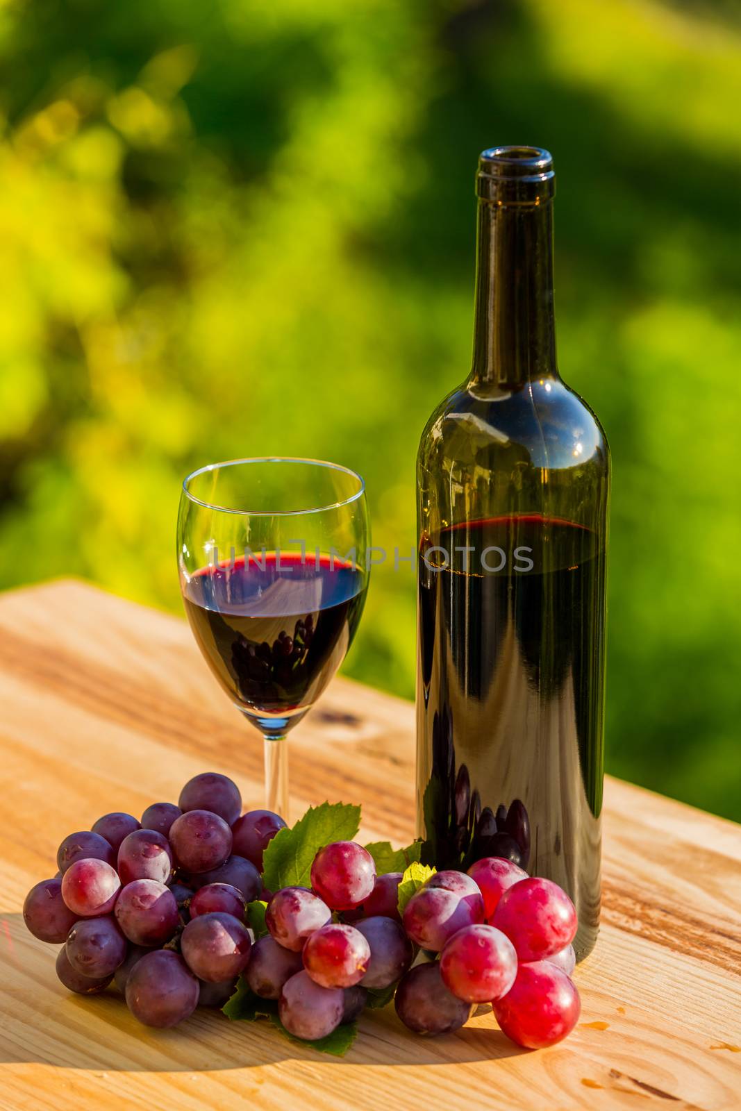 wine bottle and grapes on wooden table, outdoor