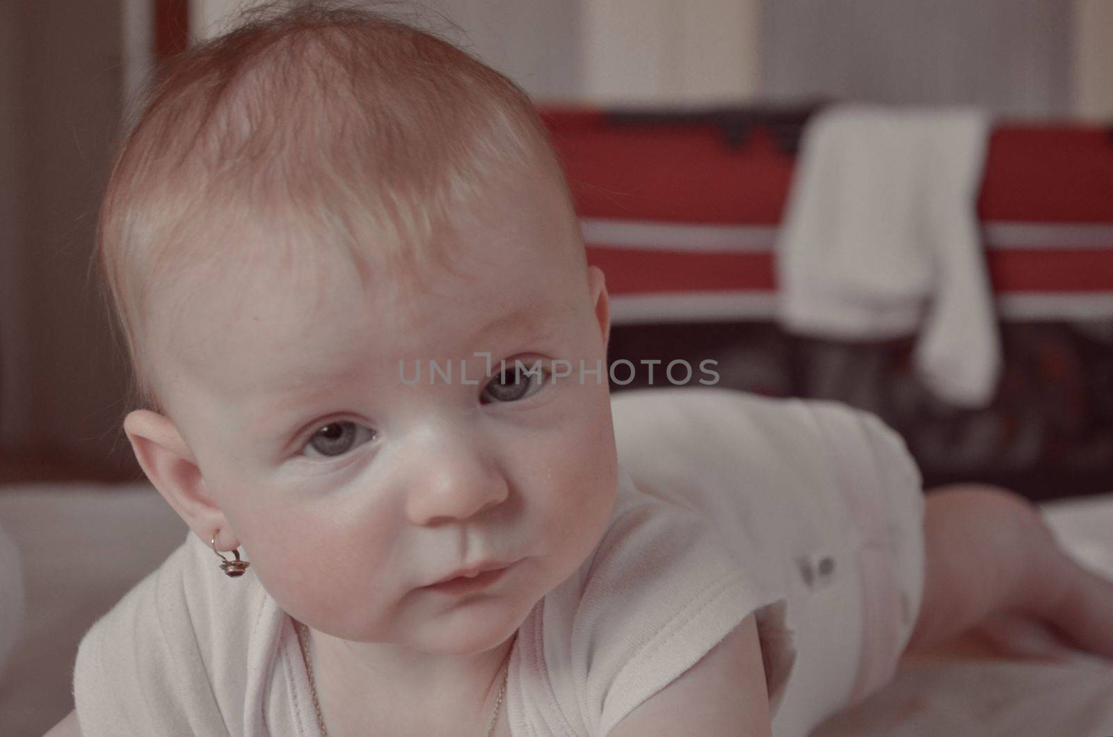 Pretty baby girl crawling on the bed. Cute toddler girl lies on the bed smiling. 6 months old baby girl. Portrait of a baby girl on the bed in bedroom. Domestic room by roman_nerud