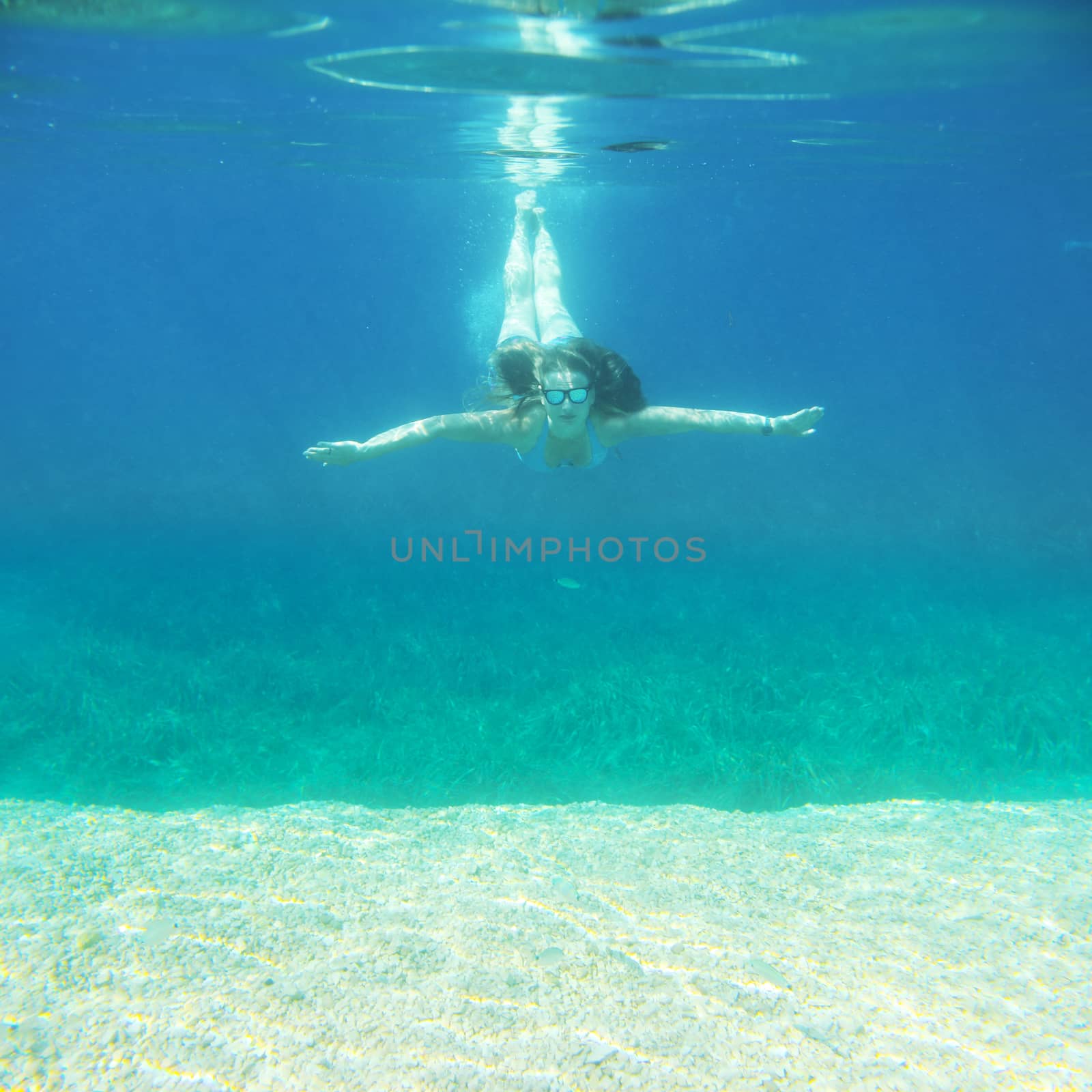 Woman swimming underwater in blue transparent sea water in summer Croatia