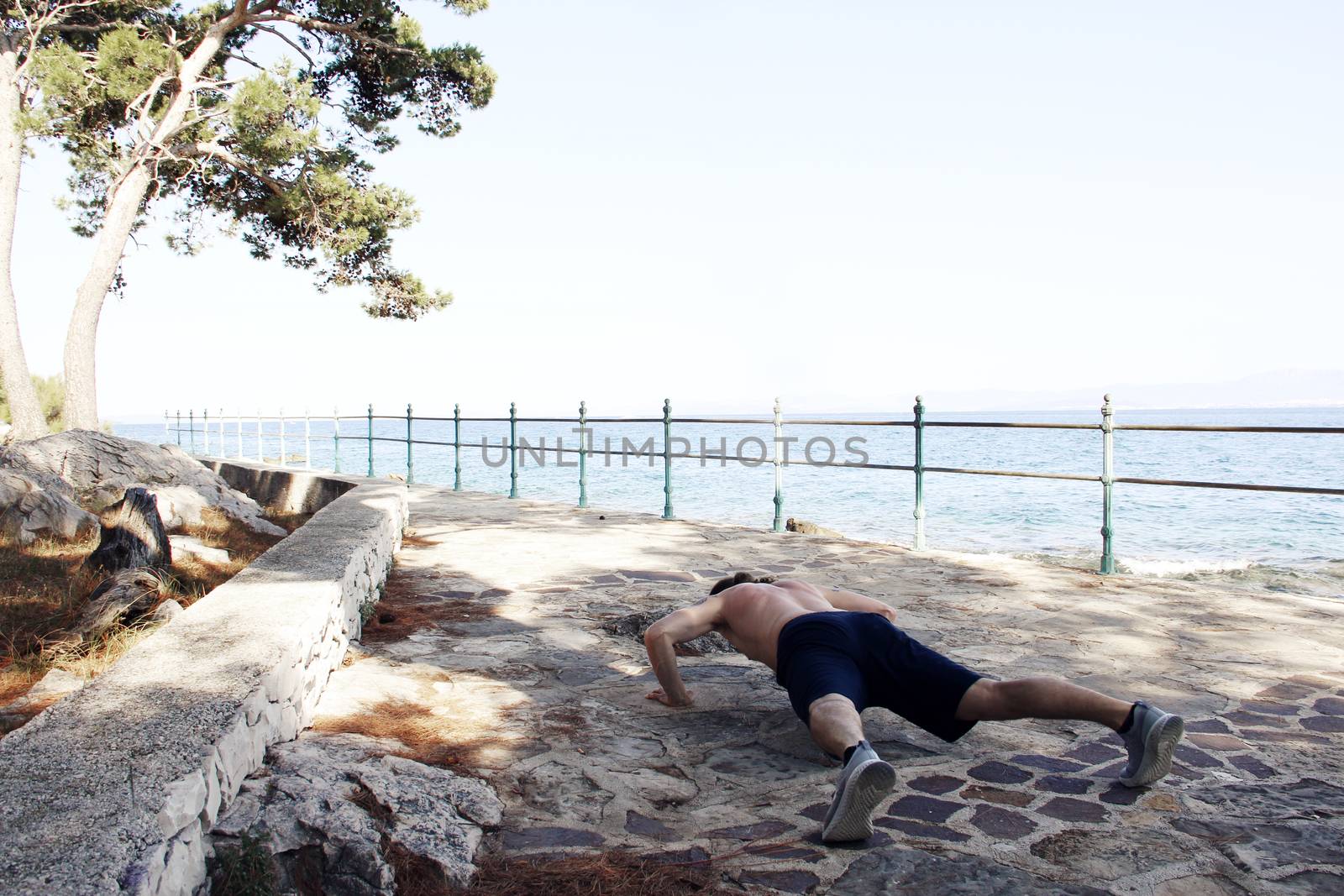 A shot of a sport man doing a push-up outdoors near sea