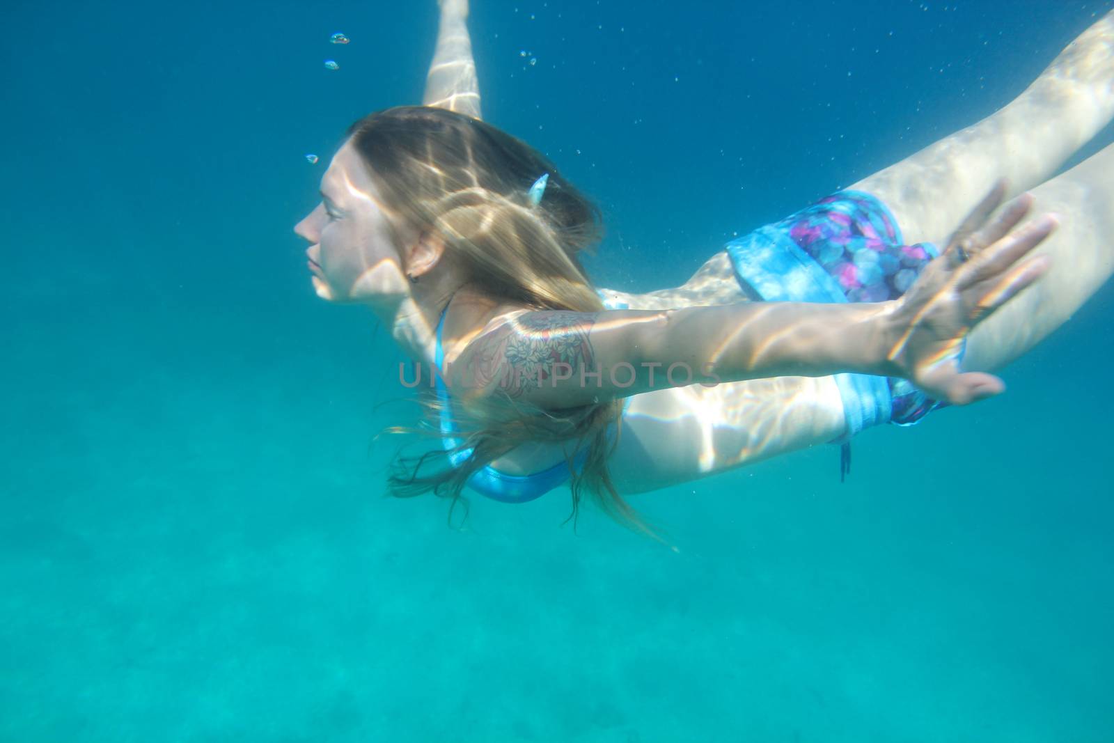 Woman swimming underwater by destillat