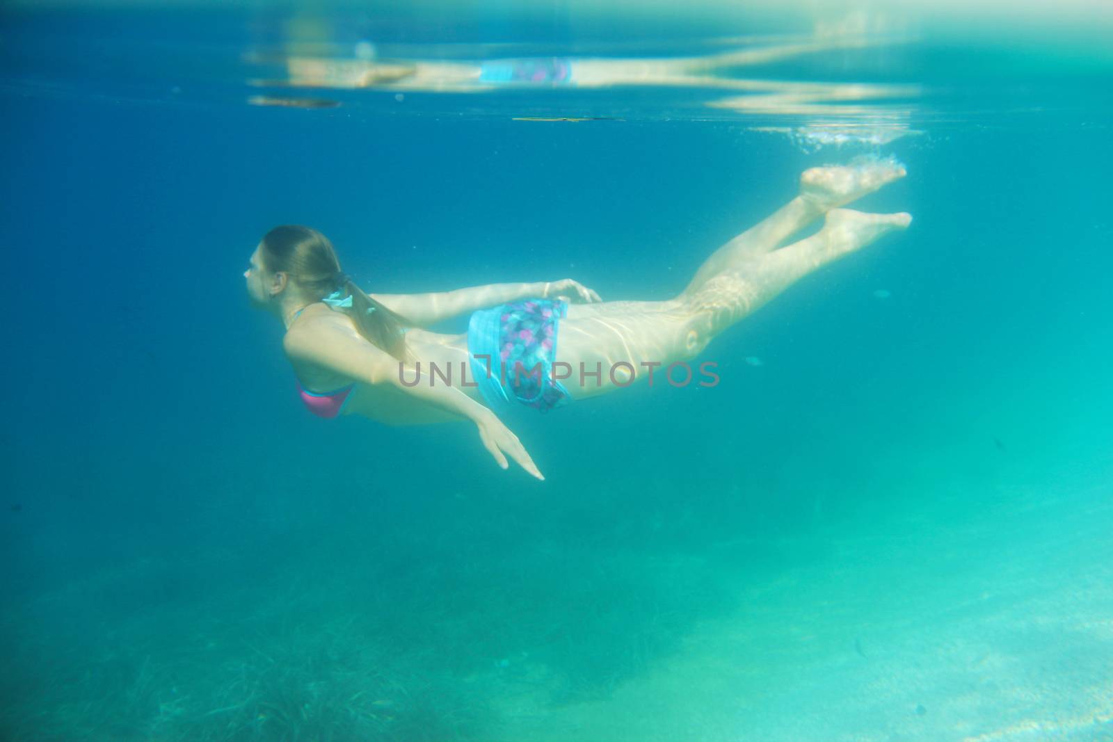 Woman swimming underwater by destillat