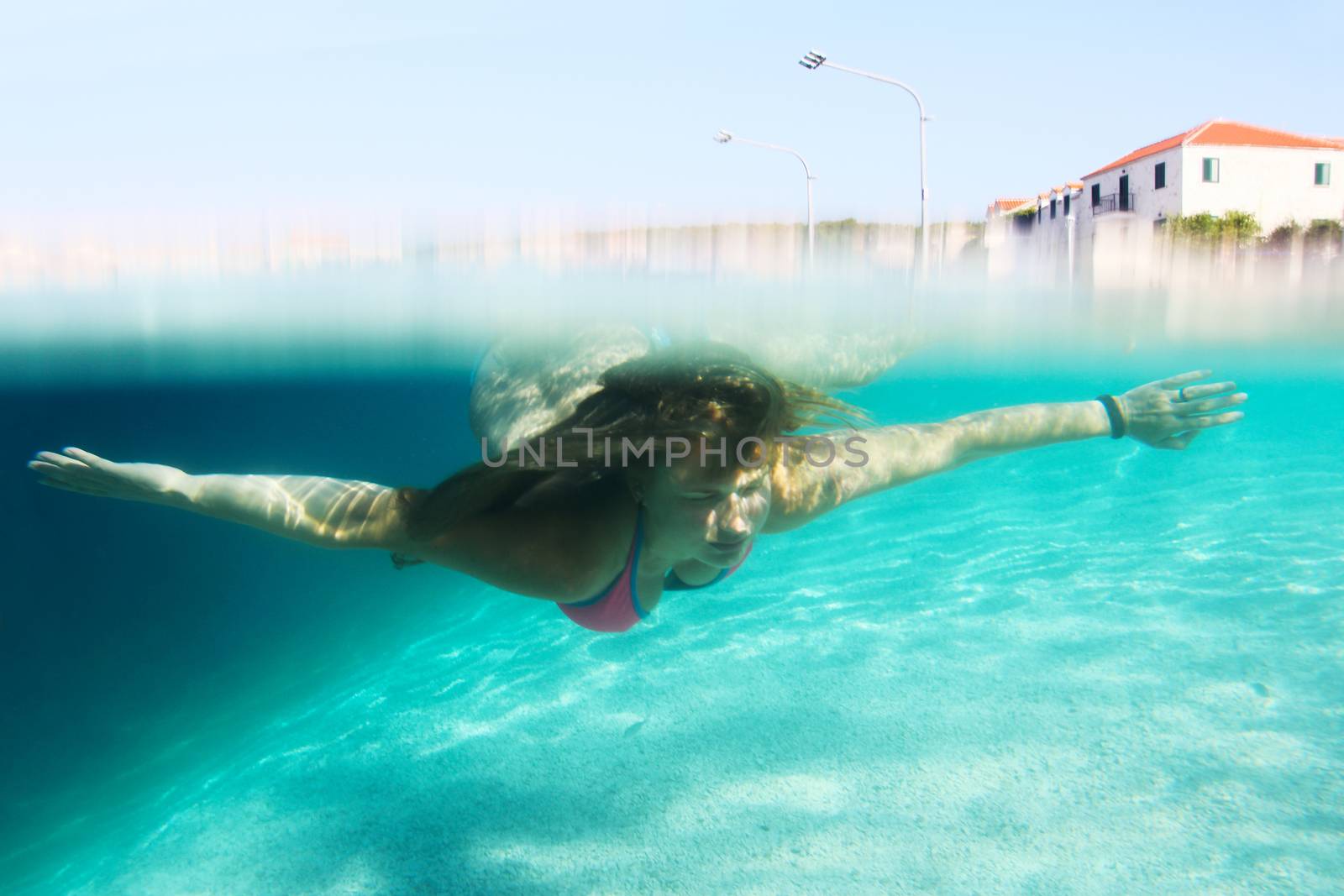 Woman swimming underwater in mediterranean adriatic sea in Croatia, old town of Sumartin