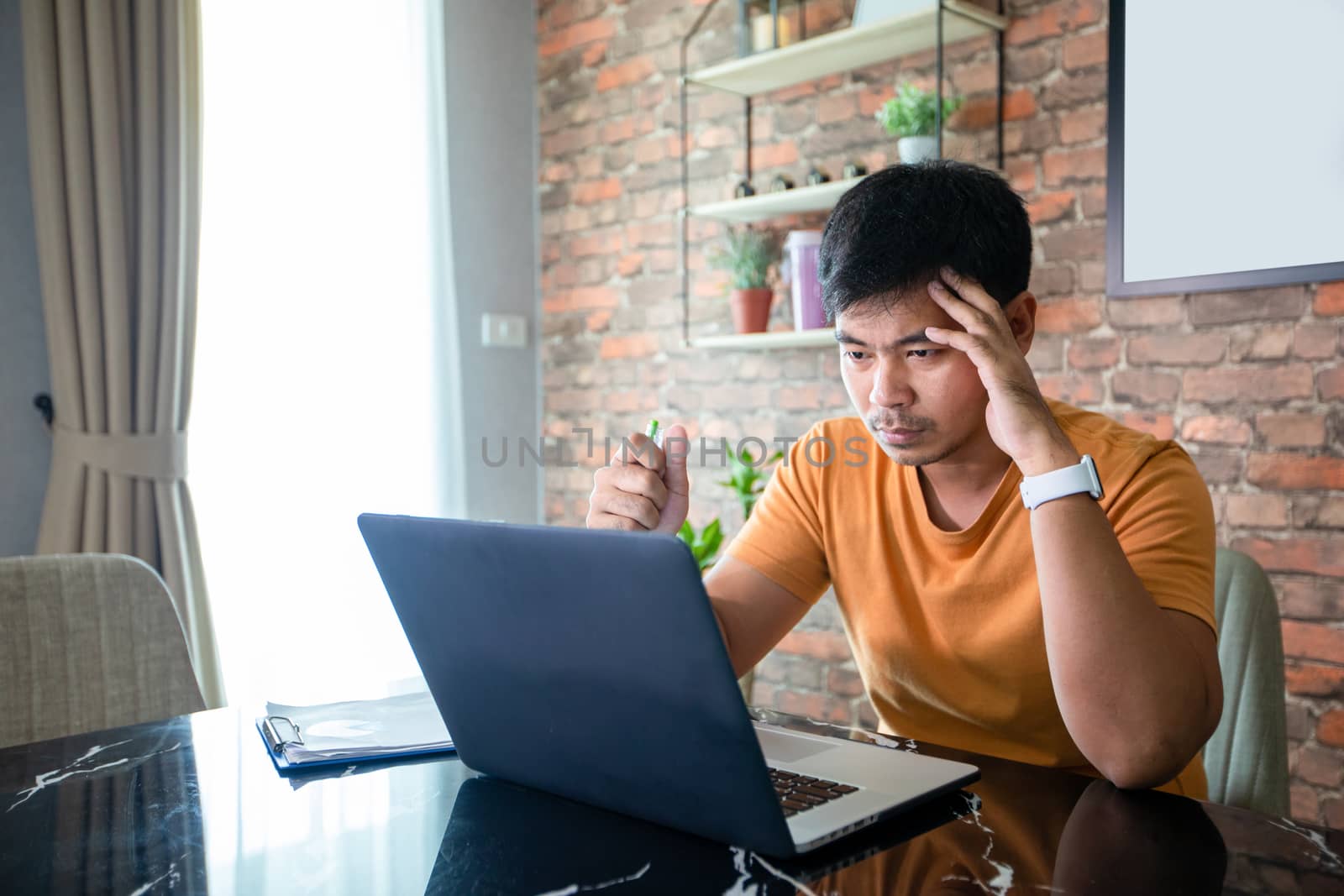 Asian man uses a notebook computer and works hard and meeting at home and he is stressed and Headache.