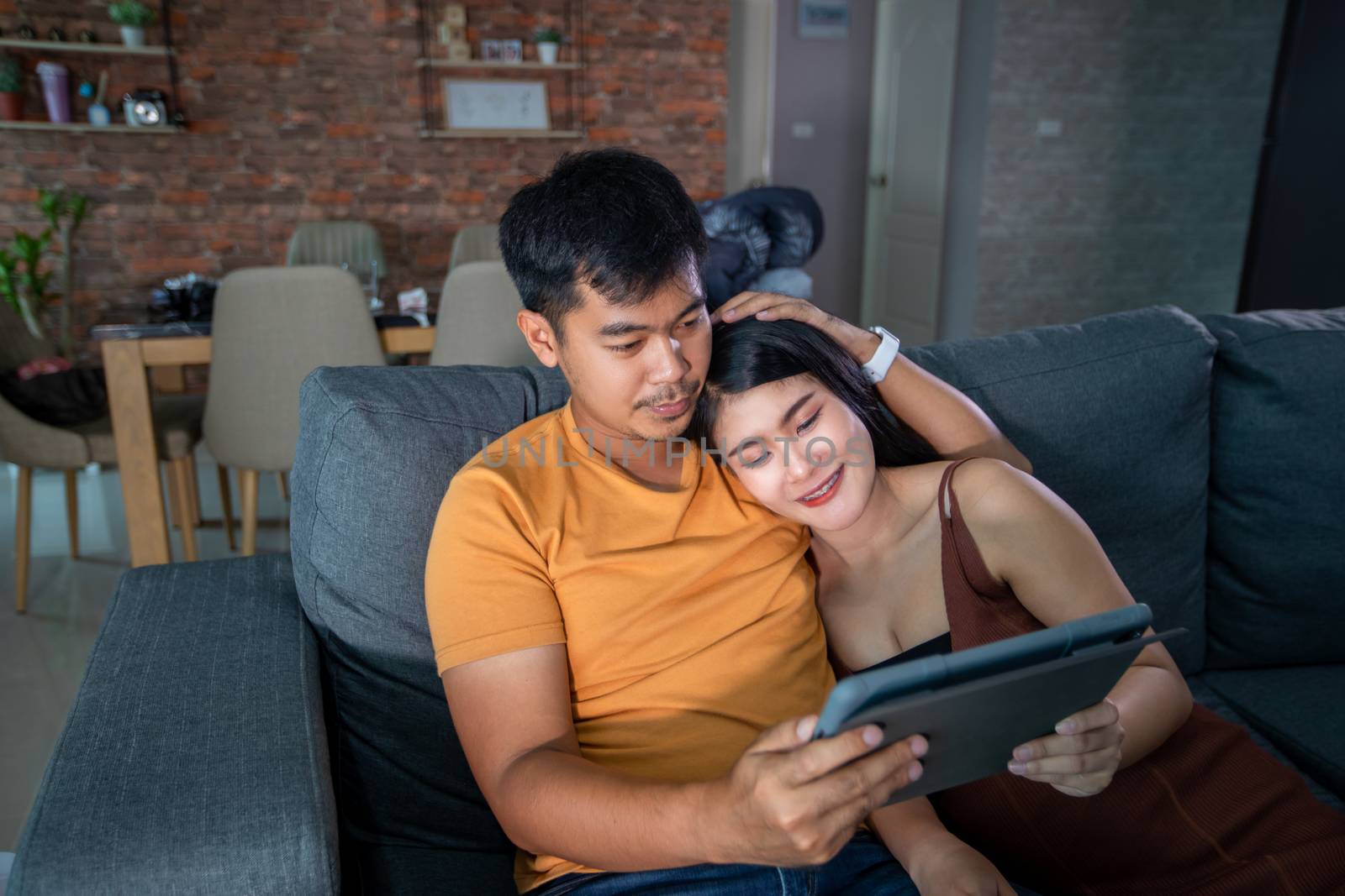 Asian Beautiful pregnant woman and husband looking ultrasound scan on a couch in the living room at home. Concept of Pregnancy health care.