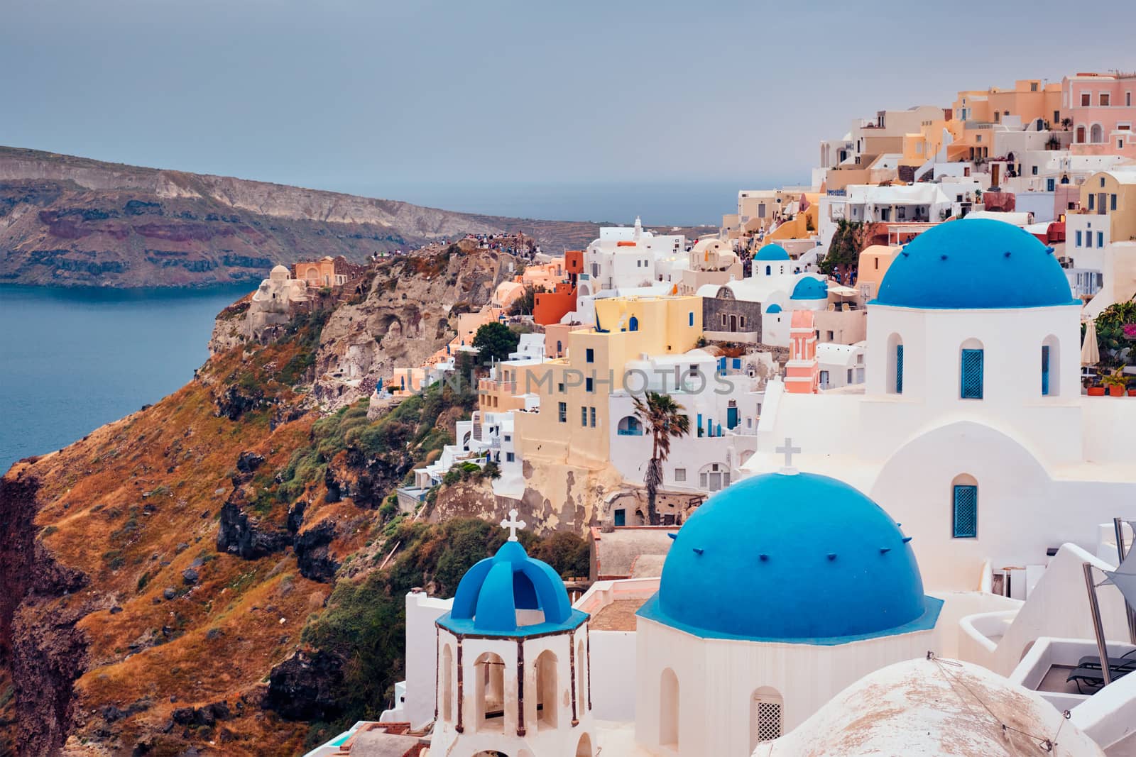 Famous greek iconic selfie spot tourist destination Oia village with traditional white houses and church in Santorini island on sunset in twilight, Greece