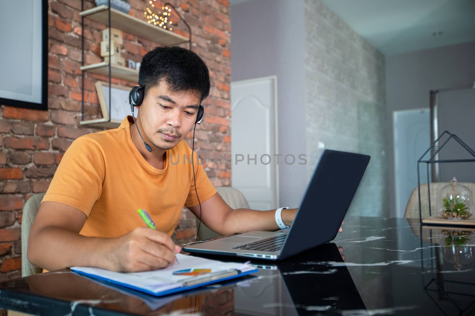 Asian businessmen is using notebook computers and wear headphones for online meetings and working from home.