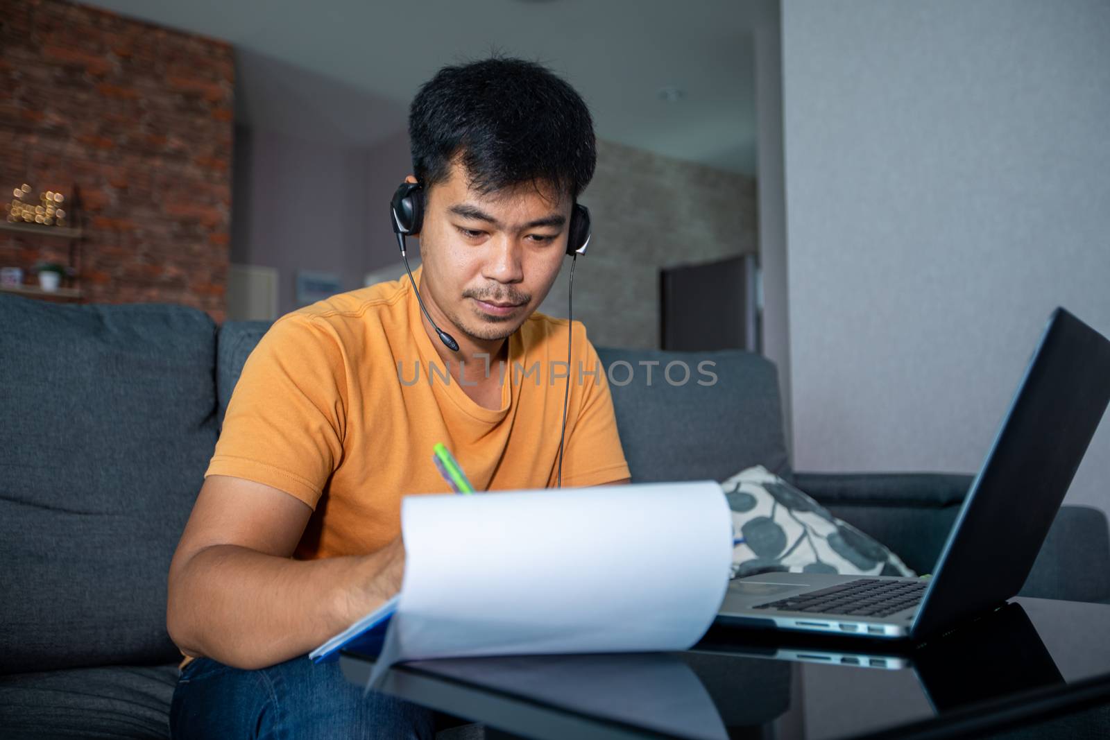 Asian businessmen is using notebook computers and wear headphones for online meetings and working from home. by Tuiphotoengineer