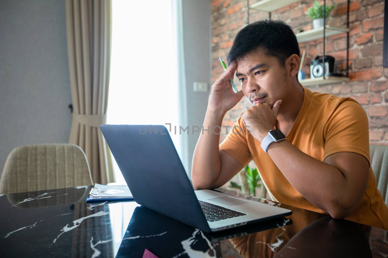 Asian man uses a notebook computer and works hard and meeting at home and he is stressed and Headache.