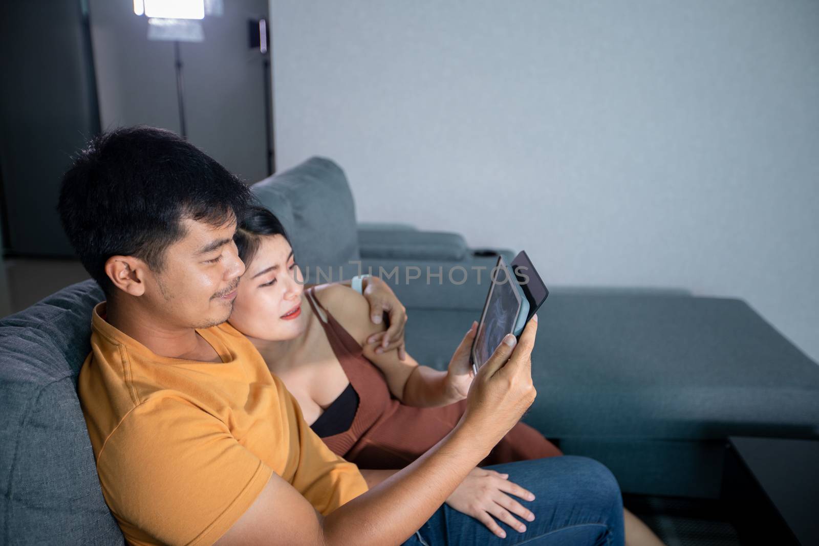 Asian Beautiful pregnant woman and husband looking ultrasound scan on a couch in the living room at home. Concept of Pregnancy health care. by Tuiphotoengineer