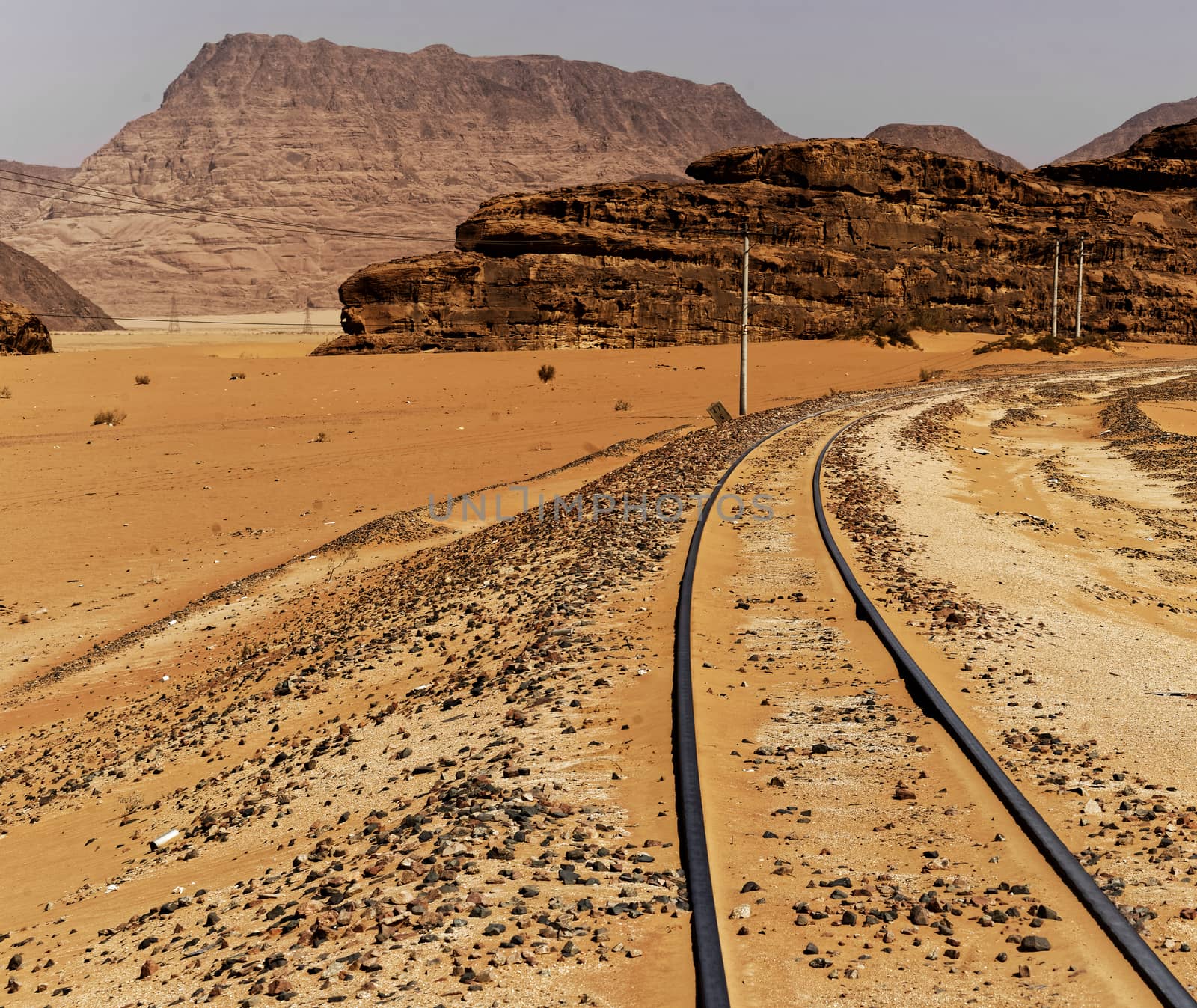One-track railway with large rock formations in the background, in the desert of Wadi Rum, Jordan by geogif
